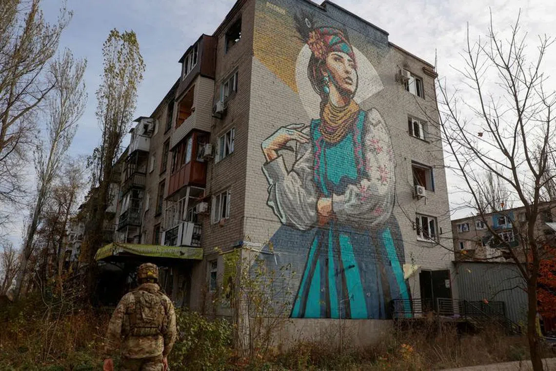 A Ukrainian serviceman walks next to a residential building heavily damaged by permanent Russian military strikes in the front line town of Avdiivka.