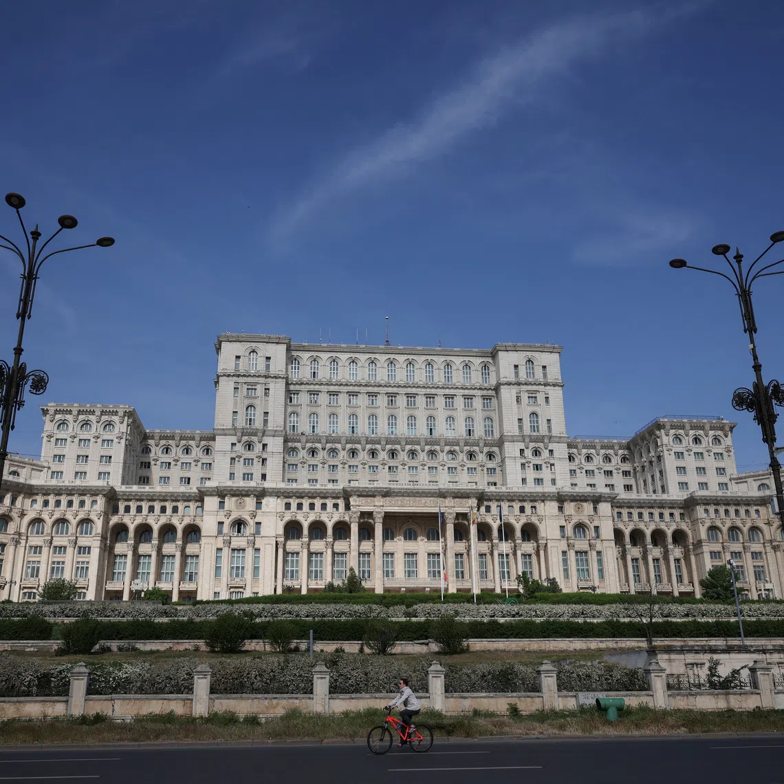 A person rides by the Palace of the Parliament in Bucharest, Romania, May 5, 2025. REUTERS/Louisa Gouliamaki