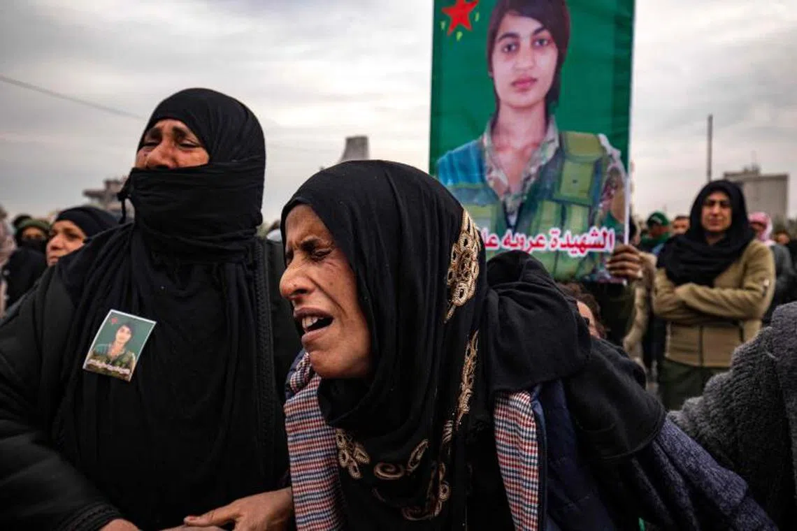 A relative mourns during the funeral procession of a member of the Women's Protection Units (YPJ), who was killed during a Turkish drone strike in the countryside of Kobani a day earlier, during her funeral in Syria's northeastern city of Qamishli on December 22, 2024. A Turkish drone killed five civilians in northeastern Syria on December 21, a war monitor said, two days after the death of Kurdish journalists in similar circumstances. (Photo by Delil SOULEIMAN / AFP)