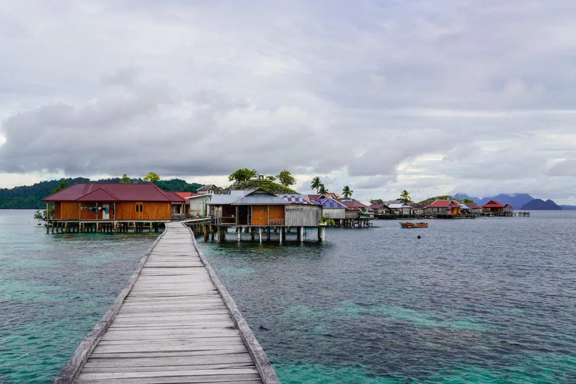 This photo taken on July 3, 2024 shows a general view of stilt houses at the village of the Bajau sea nomads in Pulau Papan in Sulawesi. The Bajau tribe spread across Indonesia, the Philippines and Malaysia have spent centuries at sea, known for its members' lung-busting diving skills that allow them to fish underwater with their bare hands or spears for longer periods than other humans. But in Pulau Papan -- a waterworld-like village in Sulawesi -- residents say they have turned to new income streams as fish stocks fall, government pressure forces them to land and technology shifts their habits. (Photo by Jack MOORE / AFP) / To go with 'INDONESIA-CULTURE-SOCIETY-INDIGENOUS, FOCUS' by Jack MOORE