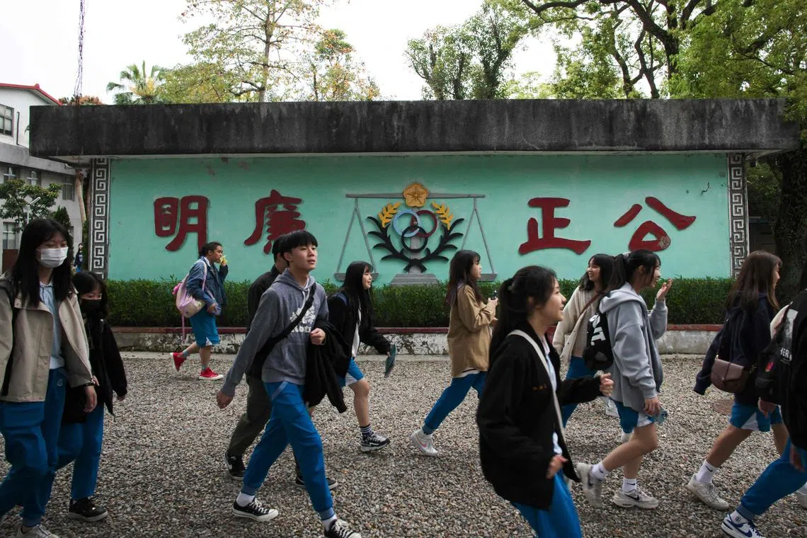 Students walk past a slogan reading "Fair and Honest" inside the Jing-Mei White Terror Memorial Park in New Taipei City on March 14, 2024. (Photo by Sam Yeh / AFP)