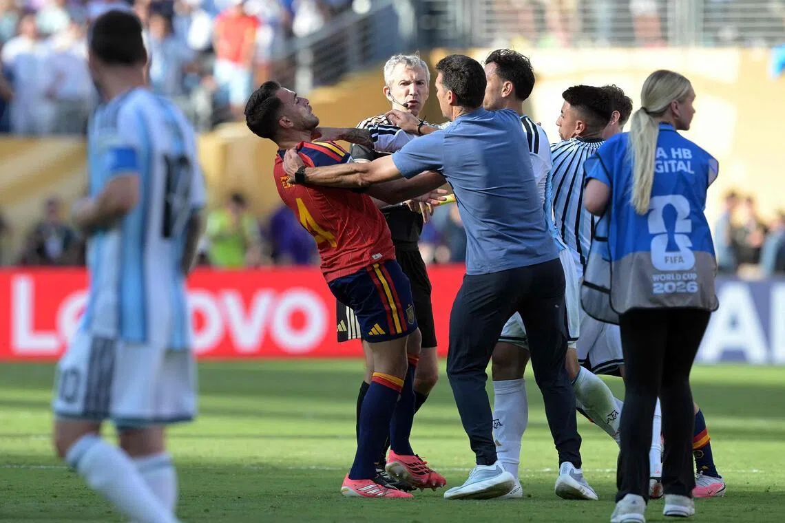 Argentina coach Lionel Scaloni (back to camera) tries to intervene as Argentina midfielder Leandro Paredes clashes with Spain defender Eric Garcia (in red) after the World Cup final on July 19.