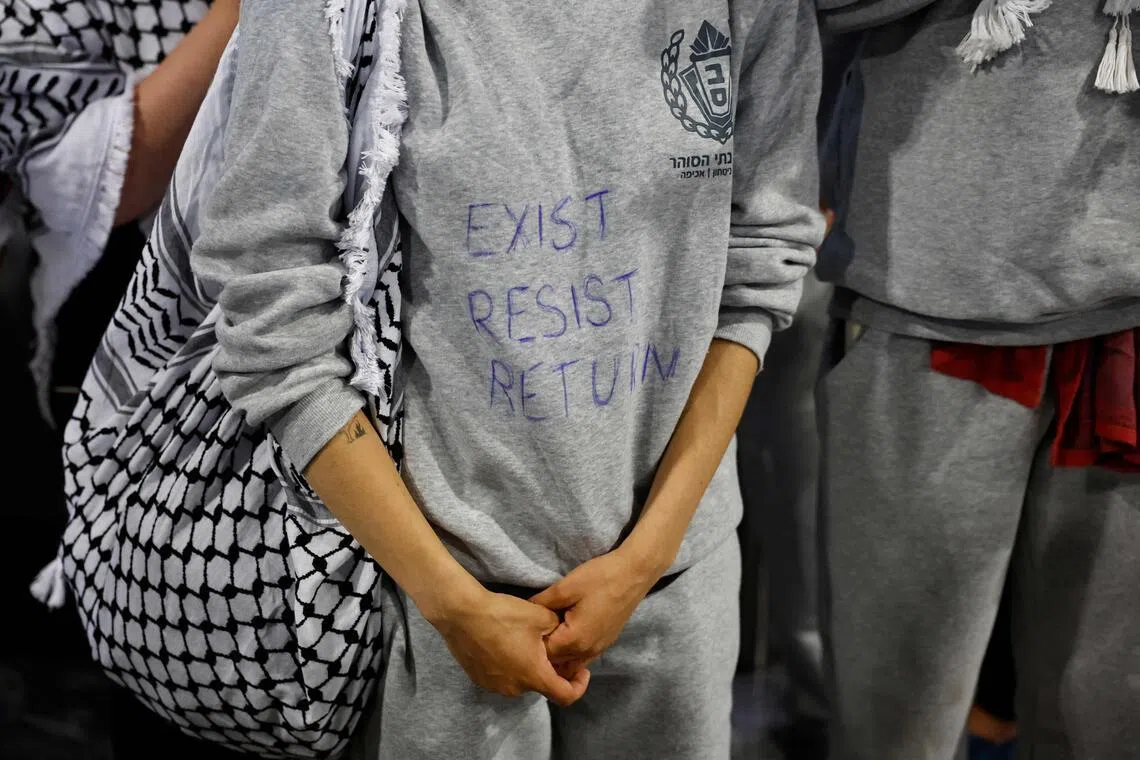 A French activist detained and deported by Israel following the interception of their Gaza-bound flotilla wearing a sweat shirt with written "Exist, resist, return".