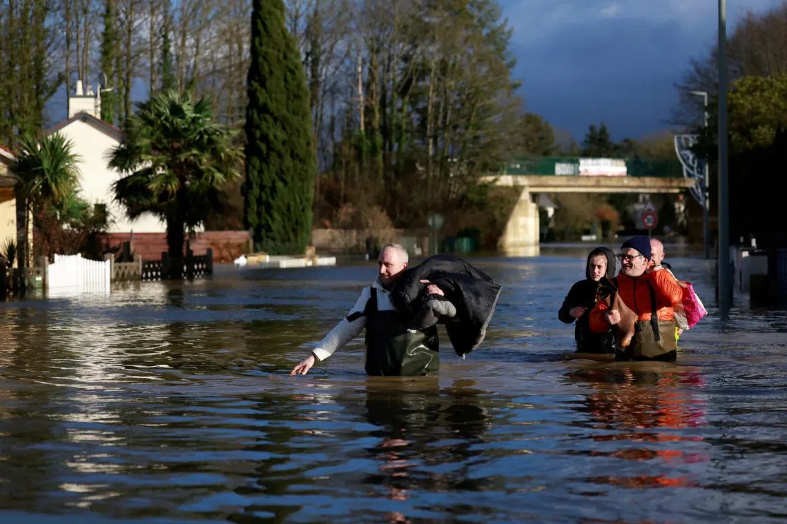 Residents walk in a flooded street in Guipry-Messac as the Vilaine river overflows after days of heavy rain causing flooding.