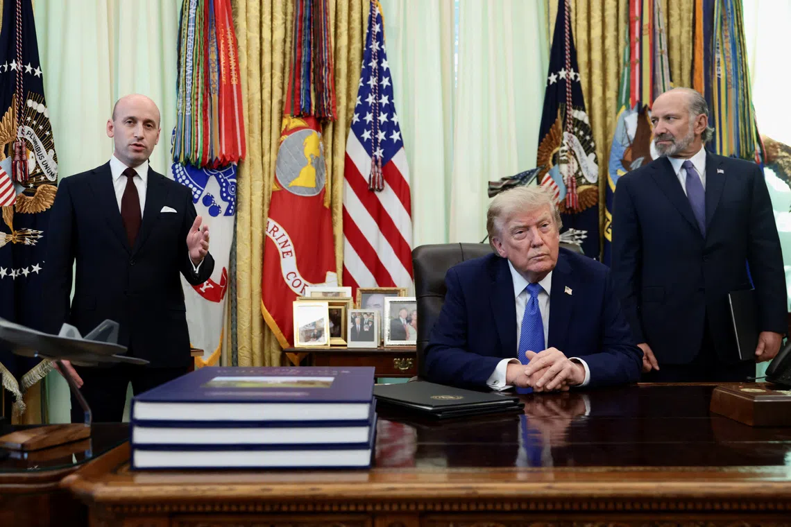 Three men in suits are positioned around a large desk in a formal office.