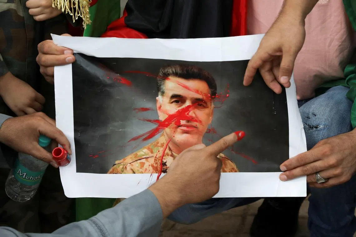 Afghan nationals paint over a picture of Pakistan's Inter-Services Intelligence (ISI) Chief, Lieutenant General Faiz Hameed, as they hold a protest against Pakistan near a police station in New Delhi, India, September 10, 2021. REUTERS/Anushree Fadnavis/File Photo