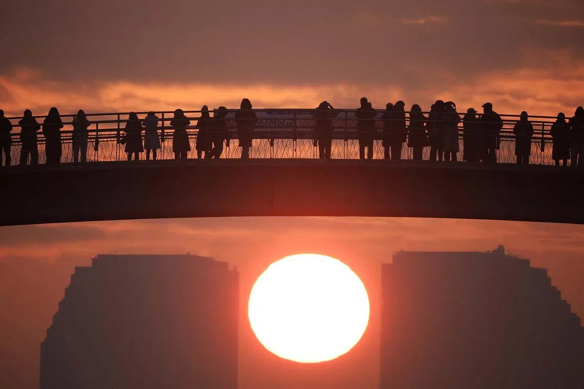 People on a bridge looking at the first sunrise of the year at a park in Seoul, South Korea, Jan 1, 2024.