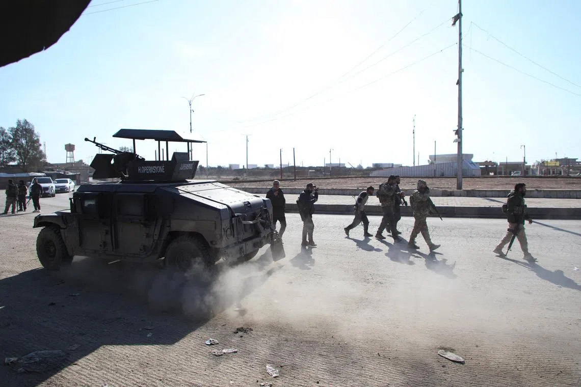 Syrian Democratic Forces (SDF) fighters walk near an armored vehicle, following clashes between SDF and Syrian government forces, in Hasakah, Syria, January 20, 2026. REUTERS/Orhan Qereman