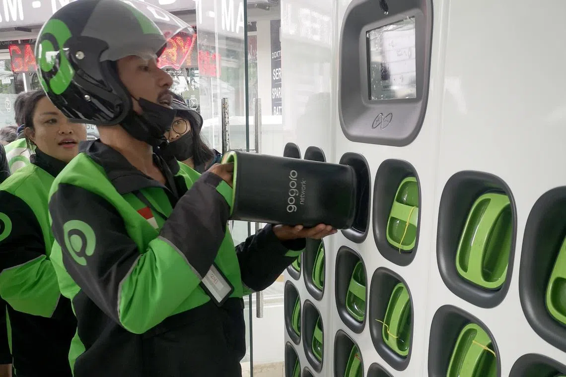 A ride hailing e-motorcycle driver swaps a near death battery with a fresh one at a battery swapping station in Bali.