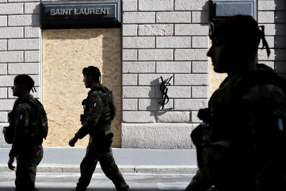 Members of the military walk by a boarded-up Saint Laurent store, ahead of a protest called by the October 17 Movement, in Milan, Italy, on Oct 24.