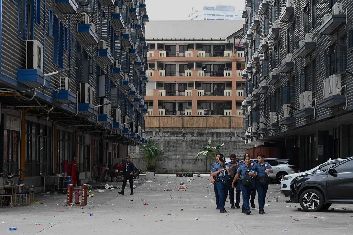Policemen walk inside a compound, where police raided buildings in Metro Manila on June 27, 2023. Philippine police said they have rescued more than a thousand people allegedly trafficked into the country to work for an online casino in the capital Manila. Chinese, Vietnamese, Singaporean and Malaysian nationals were among those found when police raided buildings inside a compound in the capital (Photo by JAM STA ROSA / AFP)