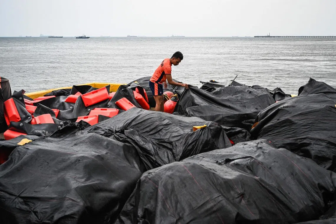 A coast guard personnel readies a containment boom in case a massive oil spill hits waters north of the capital Manila.