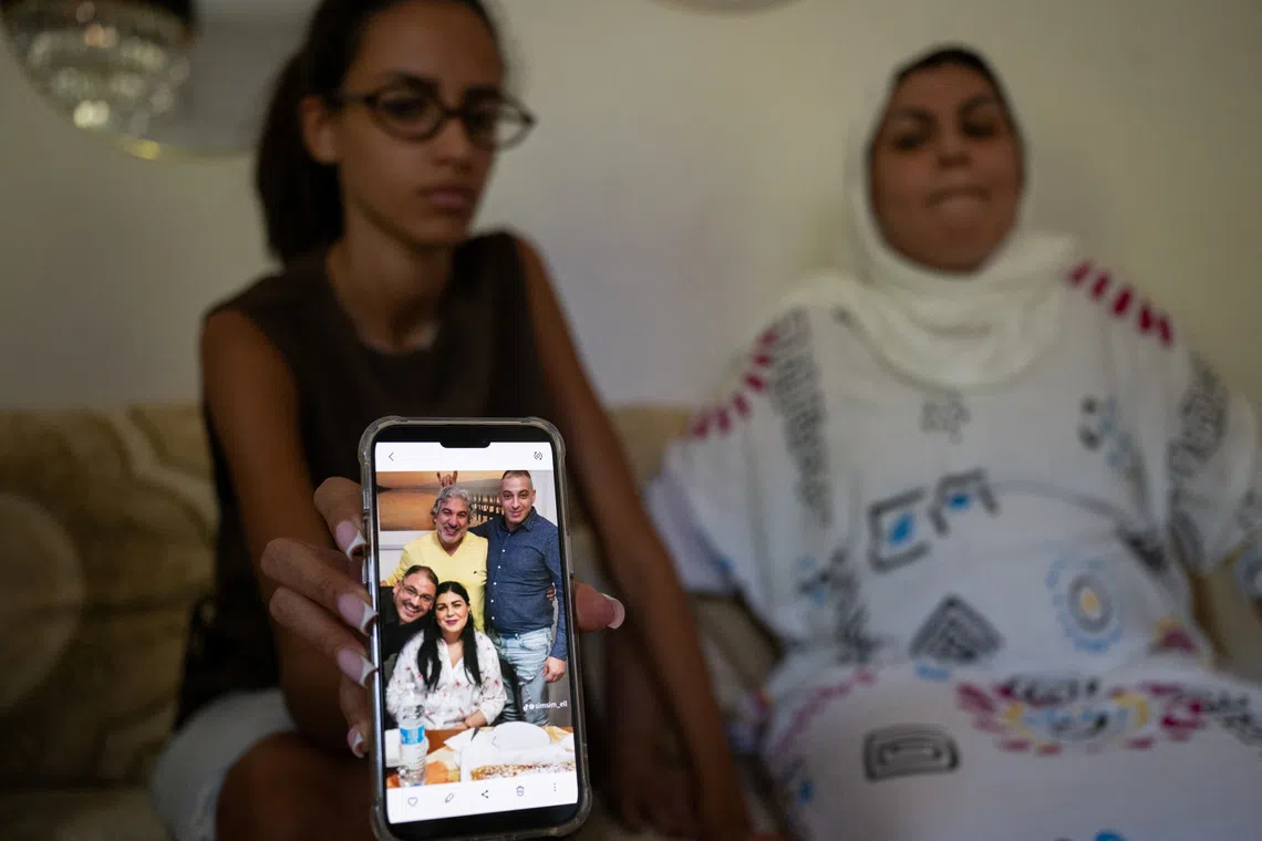 Yossra, the niece of Abderrahim Fakir, holds a mobile phone displaying a family photograph that includes Fakir, as his sister Khadija sits beside Yossra, in Bologna, Italy, July 29, 2026. REUTERS/Michele Lapini
