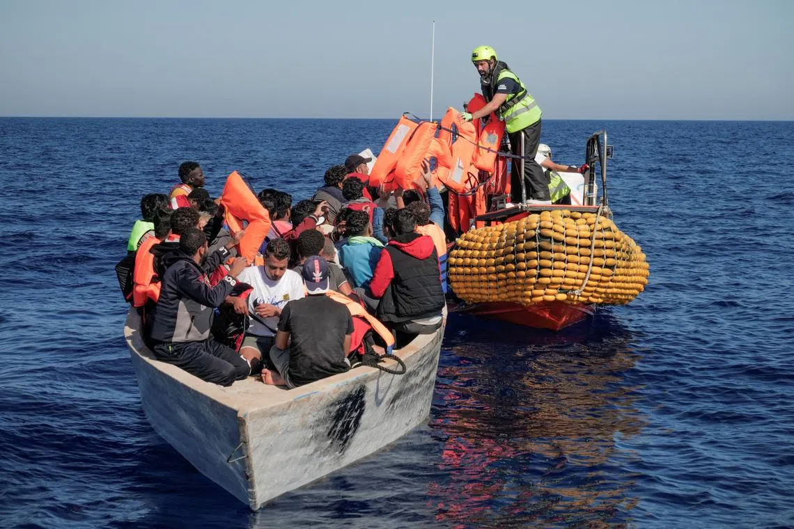 Crew members of the NGO rescue ship Ocean Viking handing out life jackets to migrants on an overcrowded boat in the Mediterranean, on Oct 25, 2022.