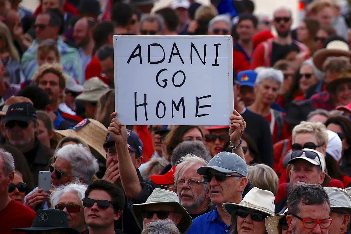 FILE PHOTO: A protester holds a sign as he participates in a national Day of Action against the Indian mining company Adani's planned coal mine project in north-east Australia, at Sydney's Bondi Beach in Australia, October 7, 2017.      REUTERS/David Gray/File Photo