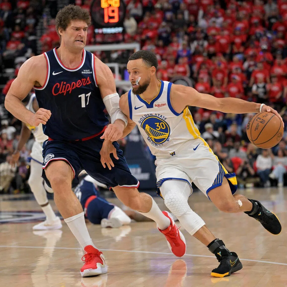 Los Angeles Clippers center Brook Lopez defends Golden State Warriors guard Stephen Curry in the second half at Intuit Dome.