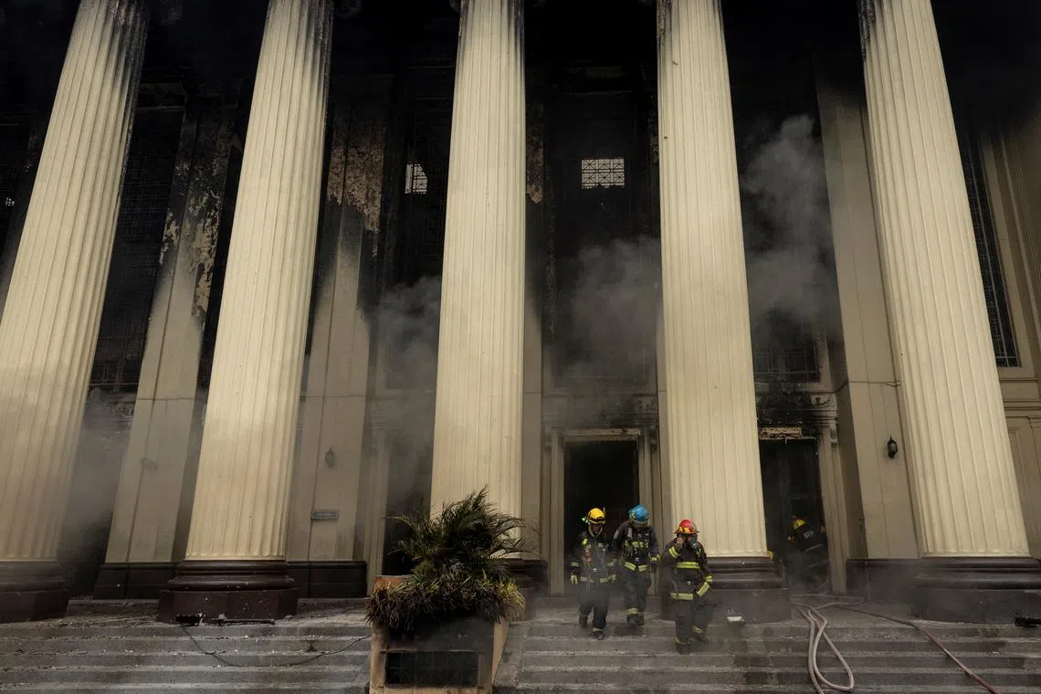Firefighters walk out of the burning Manila Central Post Office building following a massive fire, in Manila, Philippines, May 22, 2023. 