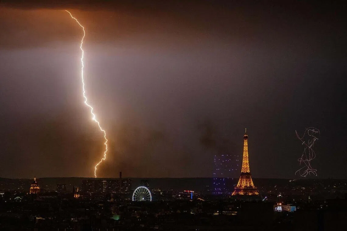 TOPSHOT - A ligthing strikes as fireworks light up around the Eiffel Tower during a choreographed firework and drone show to celebrate Bastille Day, in Paris, on July 13, 2026, on the eve of the annual Bastille Day Parade in the French capital. (Photo by DIMITAR DILKOFF / AFP)