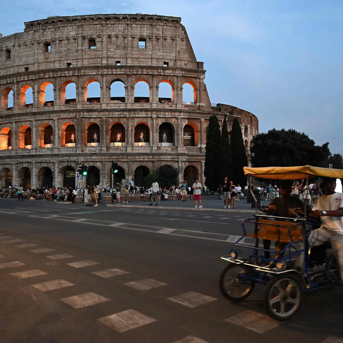 Pedestrians walk past the Rome’s ancient Colosseum during “A Night at the Colosseum” tour, a guided visit.