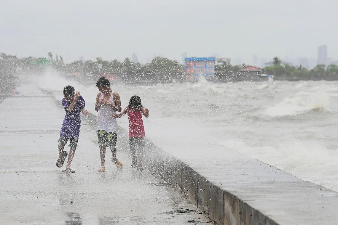 Children walking along a sea wall at Navotas in Metro Manila on July 26, 2023, as Super Typhoon Doksuri passes close to the northern tip of Luzon island. 