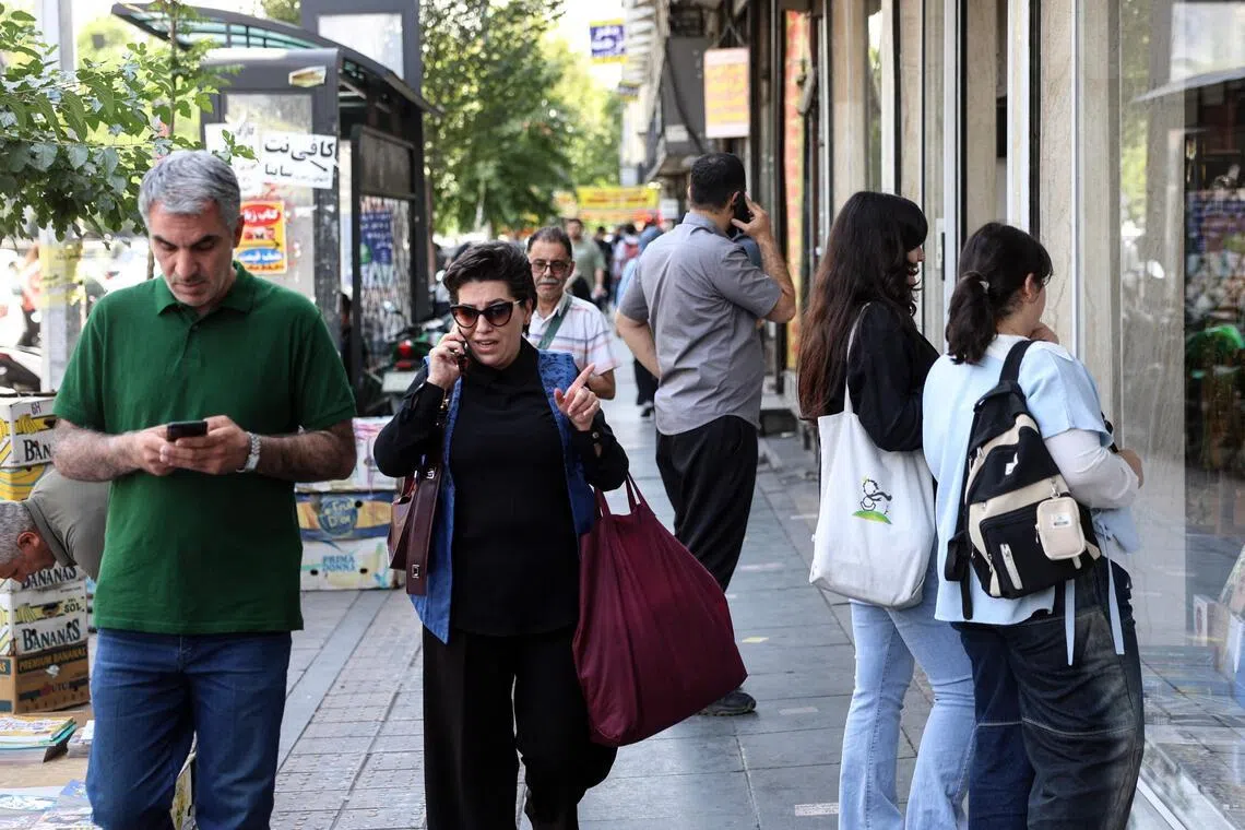 Iranians walk through a street in Tehran on June 18. The United States and Iran have signed a deal to end the Middle East war, with a ceremony set for June 19 in Switzerland that will mark the start of a 60-day negotiation period.