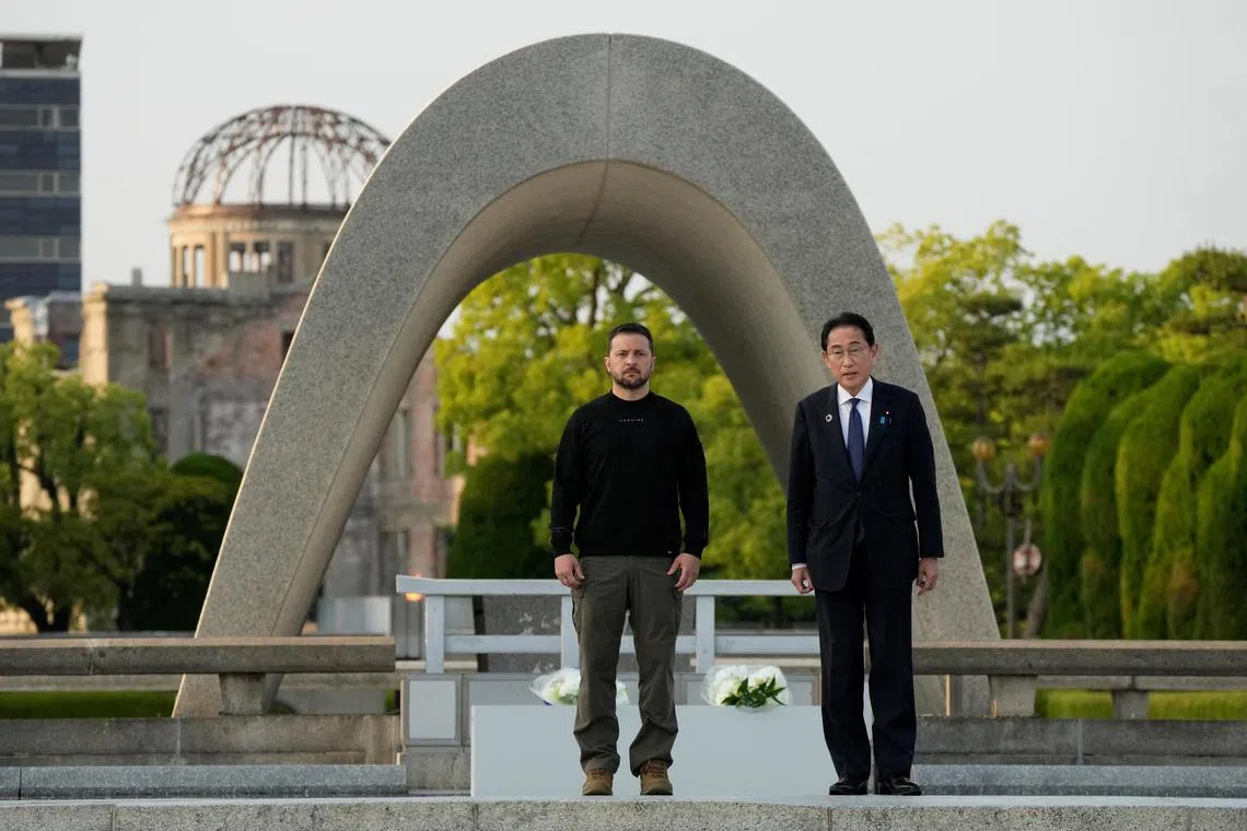Ukrainian President Volodymyr Zelenskiy and Japanese Prime Minister Fumio Kishida, pose for a photo after laying a wreath in front of the Cenotaph for the Victims of the Atomic Bomb at the Hiroshima Peace Memorial Park, after Zelenskiy was invited to the Group of Seven nations' summit in Hiroshima, Japan, May 21, 2023. The Atomic Bomb Dome is seen in the background. Eugene Hoshiko/Pool via REUTERS