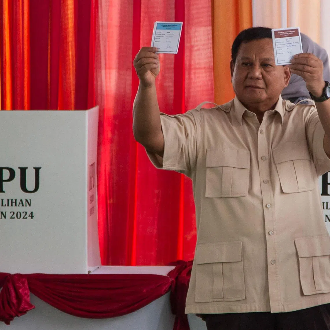 Indonesian President Prabowo Subianto shows the ballot papers while voting at a simultaneous regional election in Bogor, West Java on November 27, 2024. Indonesians vote to pick local leaders in the country's biggest simultaneous regional election, in which President Prabowo Subianto seeks to consolidate his party's gains. (Photo by ADITYA IRAWAN / AFP)