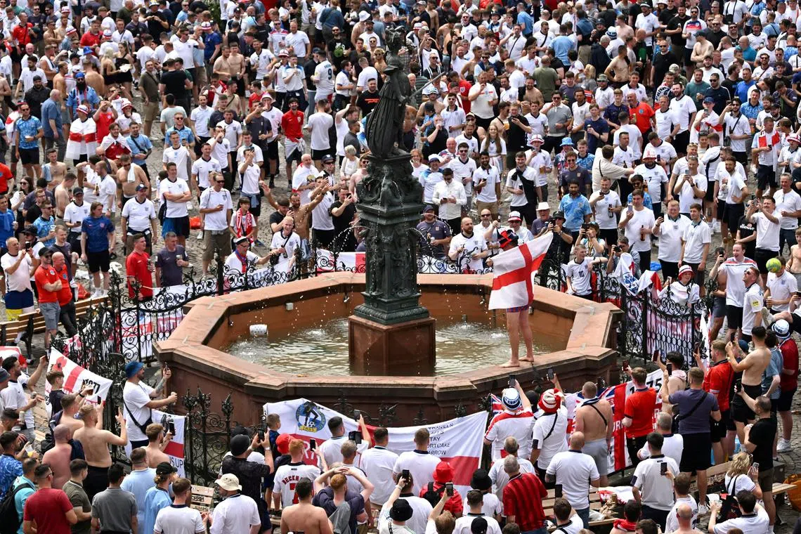 FILE PHOTO: Soccer Football - Euro 2024 - Fans gather for Denmark v England - Frankfurt, Germany - June 20, 2024 A fan holds an England flag while standing on the fountain as fans gather in Romerberg square in Frankfurt before the match REUTERS/Jana Rodenbusch/File Photo