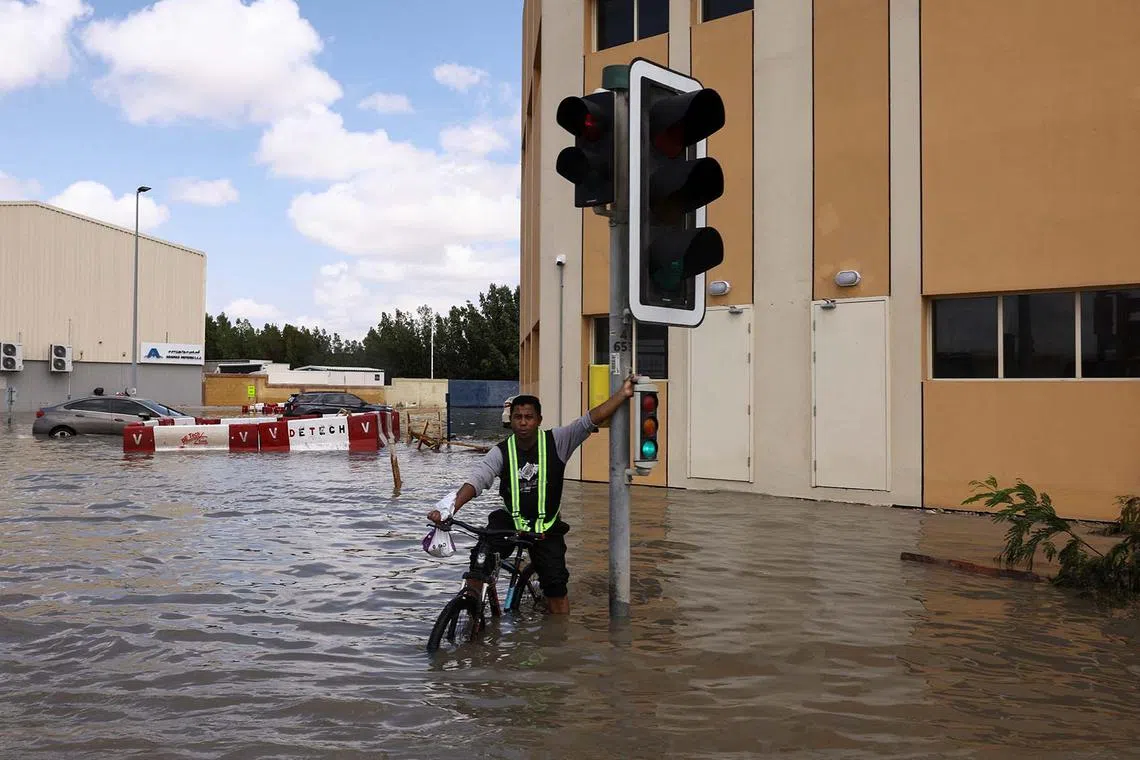 A person riding a bicycle in flood water caused by heavy rains, in Dubai, United Arab Emirates, April 17, 2024. 