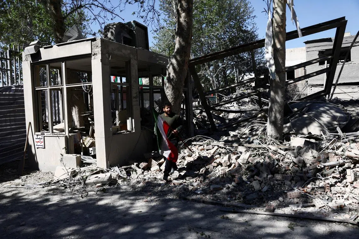 FILE PHOTO: A man carries an Iranian flag as he walks amidst the rubble of a building of the Sharif University of Technology, which was damaged in a strike, amid the U.S.-Israeli conflict with Iran, in Tehran, Iran, April 7, 2026. Majid Asgaripour/WANA (West Asia News Agency) via REUTERS /File Photo