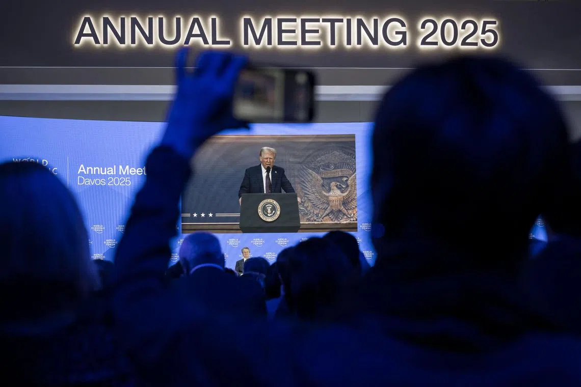 US President Donald Trump is seen on a large screen, next to Founder and executive chairman of the World Economic Forum Klaus Schwab, during his address by video conference at the World Economic Forum (WEF) annual meeting in Davos on January 23, 2025. (Photo by Fabrice COFFRINI / AFP)