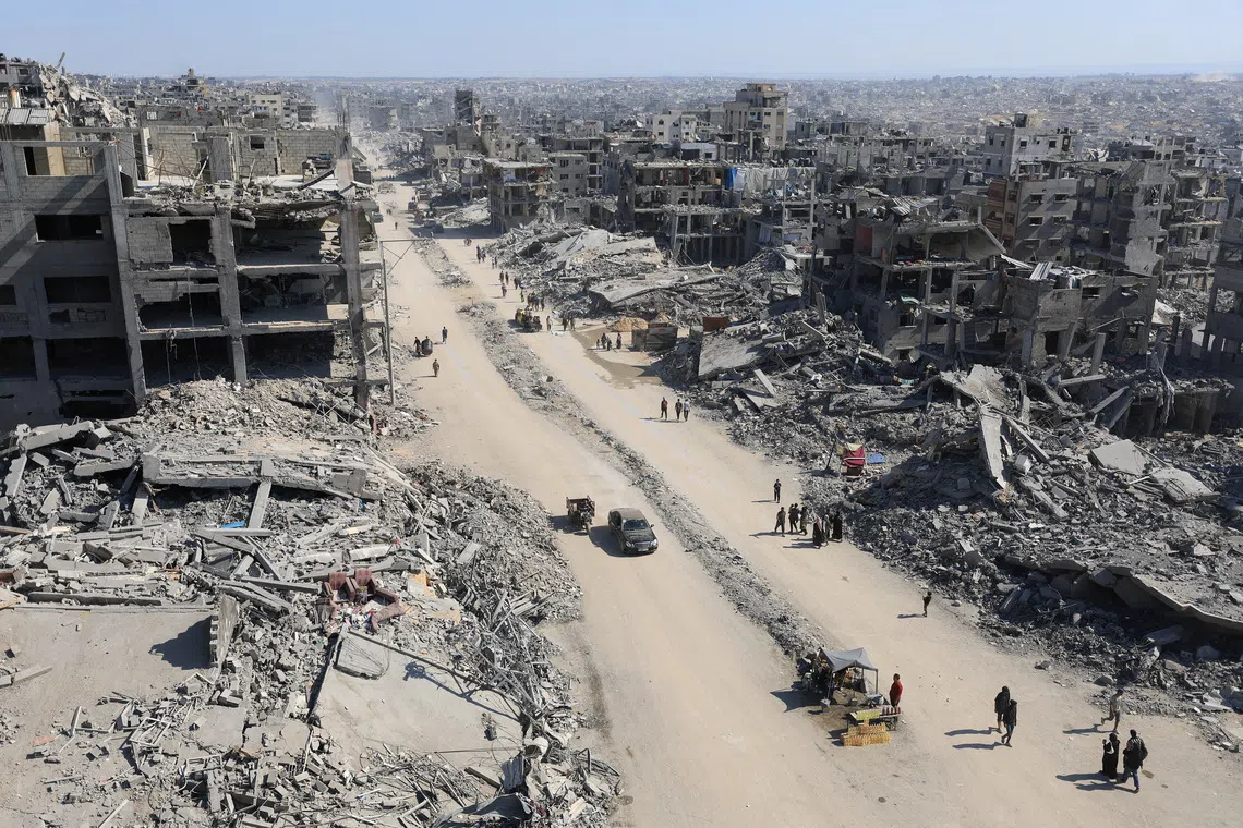 Palestinians walk past the rubble of destroyed buildings, amid a ceasefire between Israel and Hamas, in Gaza City, October 16, 2025. REUTERS/Dawoud Abu Alkas