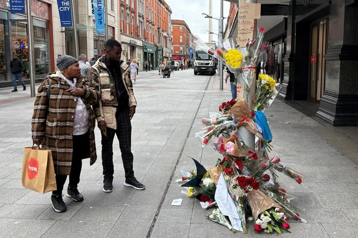People stand near flowers laid outside a department store on Henry Street where a Congolese-born man, Yves Sakila, was restrained by security guards last week and later pronounced dead in hospital, in Dublin, Ireland, May 20, 2026. REUTERS/Conor Humphries