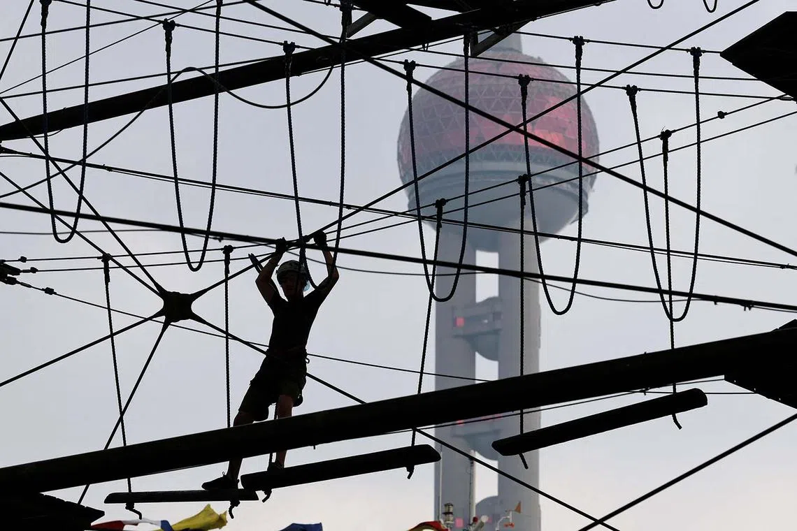 A person crossing a wire bridge at an athletic playground in Shanghai, China, July 10, 2025. 