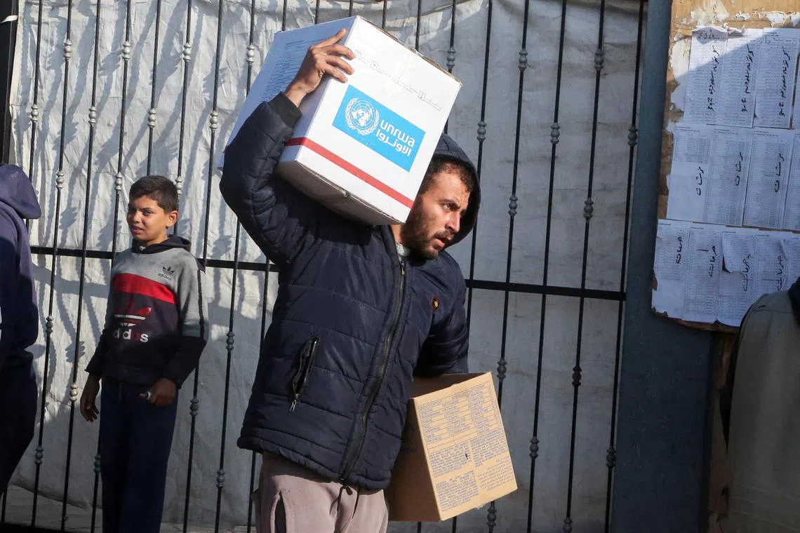 FILE PHOTO: A Palestinian man carries aid boxes provided by UNRWA outside a distribution point, amid a ceasefire between Israel and Hamas, in Khan Younis in the southern Gaza Strip, February 4, 2025. REUTERS/Hatem Khaled/File Photo