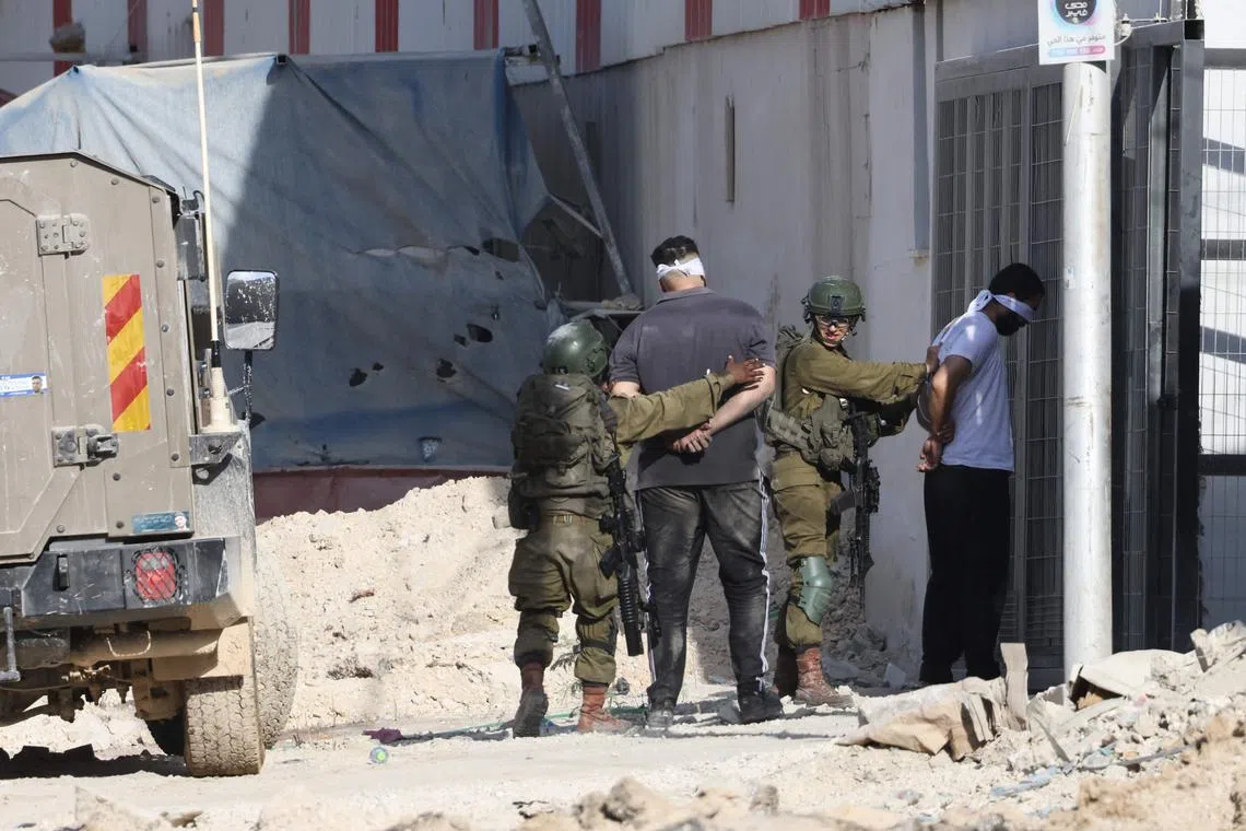 Israeli soldiers arrest two Palestinian men during a raid in the Nur Shams camp near the city of Tulkarem on Aug 28.