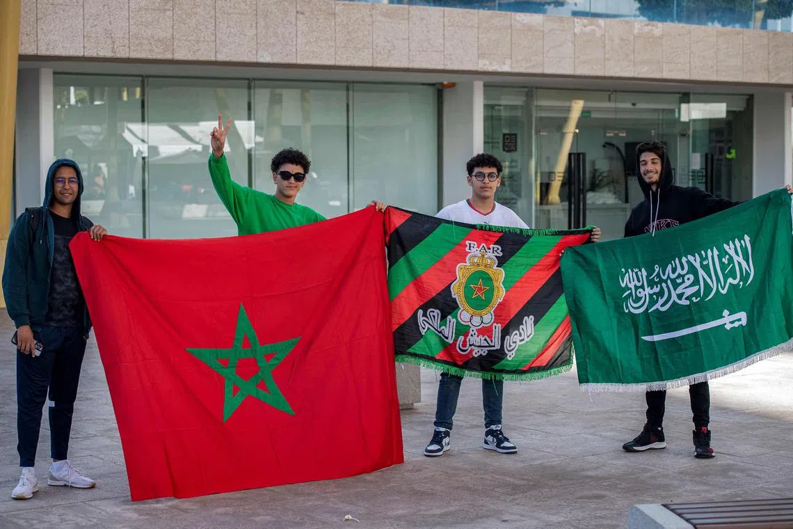 Fans of Morocco and Saudi Arabia posing for a photo with their countries' flags, showing the unity of the Arab nations.