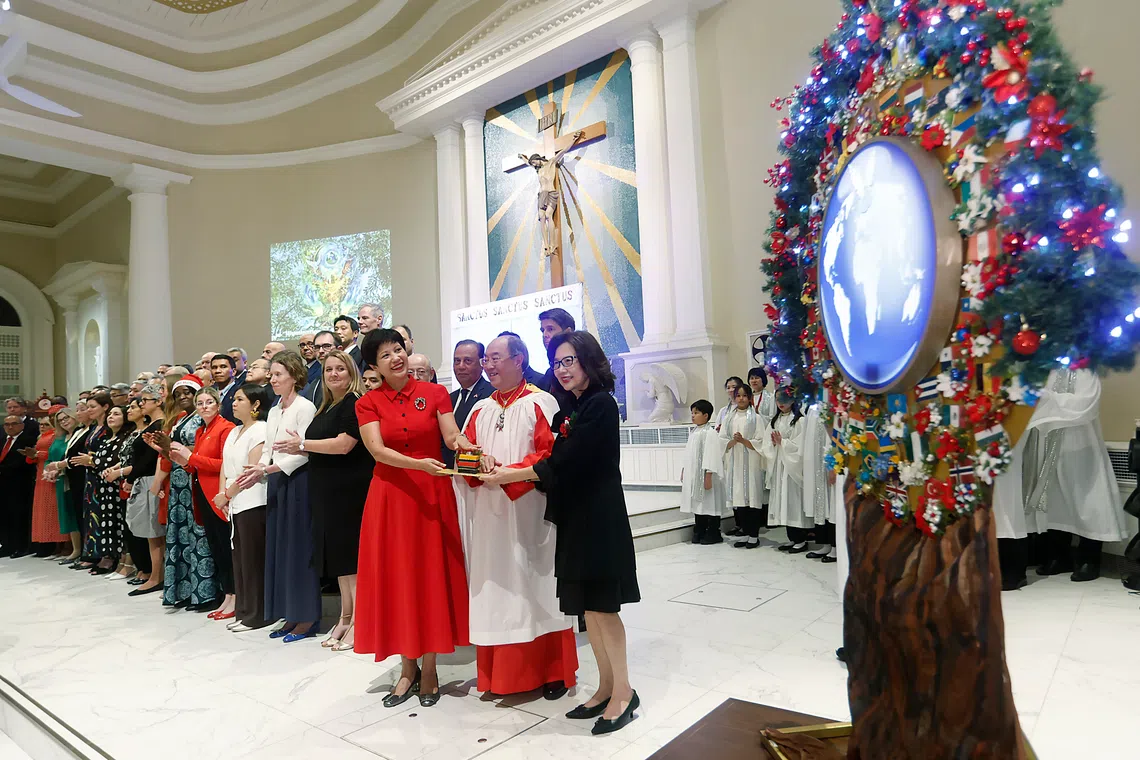 Minister in the ​PMO's office and Second Minister for Finance and National Development​, Ms Indranee Rajah (third from right) pressing a button to light up the symbolic tree of peace with the choir's founder-director Peter Low and his wife Linda. 
PHOTO: CATHEDRAL CHOIR OF THE RISEN CHRIST