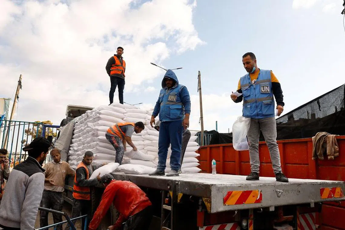 Palestinians receive flour bags distributed by UNRWA in Rafah, in the southern Gaza Strip November 21, 2023. REUTERS/Ibraheem Abu Mustafa