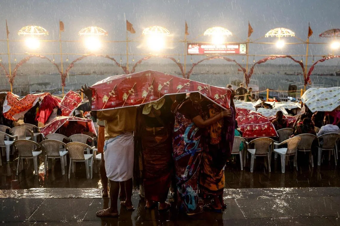 Tourists taking shelter under sheets during rainfall as they wait to attend evening prayers at Dashashwamedh ghat along the banks of river Ganges in Varanasi, India, on April 29.