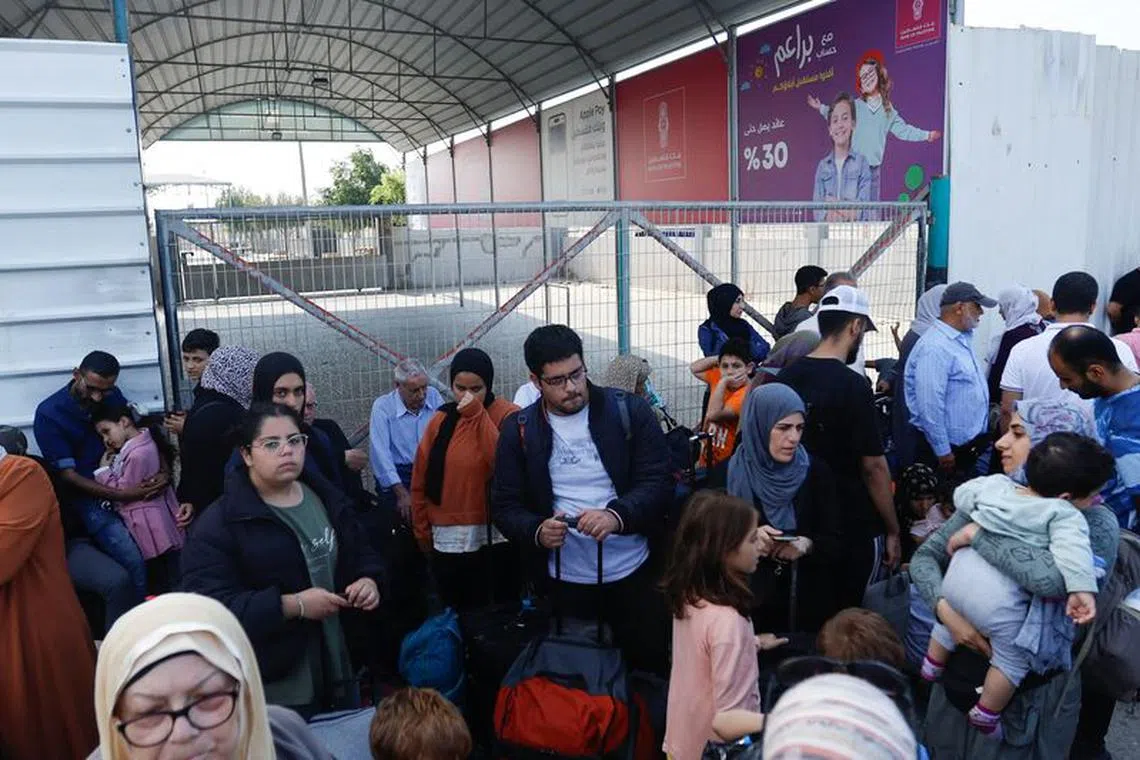 Palestinians with dual citizenship gather outside Rafah border crossing with Egypt in the hope of getting permission to leave Gaza, amid the ongoing Israeli-Palestinian conflict, in Rafah in the southern Gaza Strip October 14, 2023. REUTERS/Ibraheem Abu Mustafa