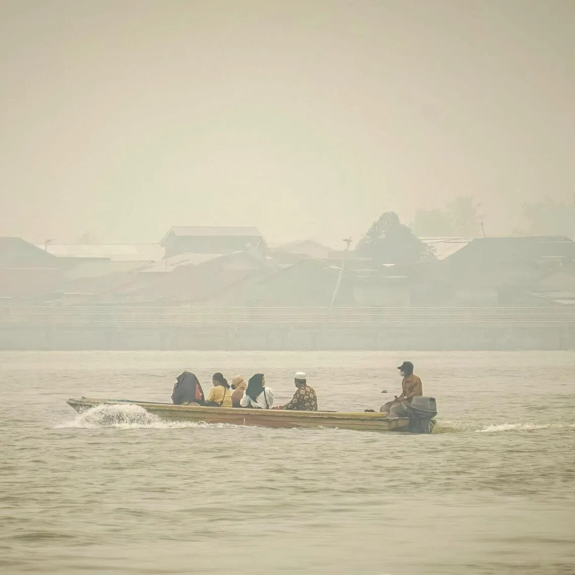 People travel on a boat as thick haze blankets a village in Pontianak, West Kalimantan.