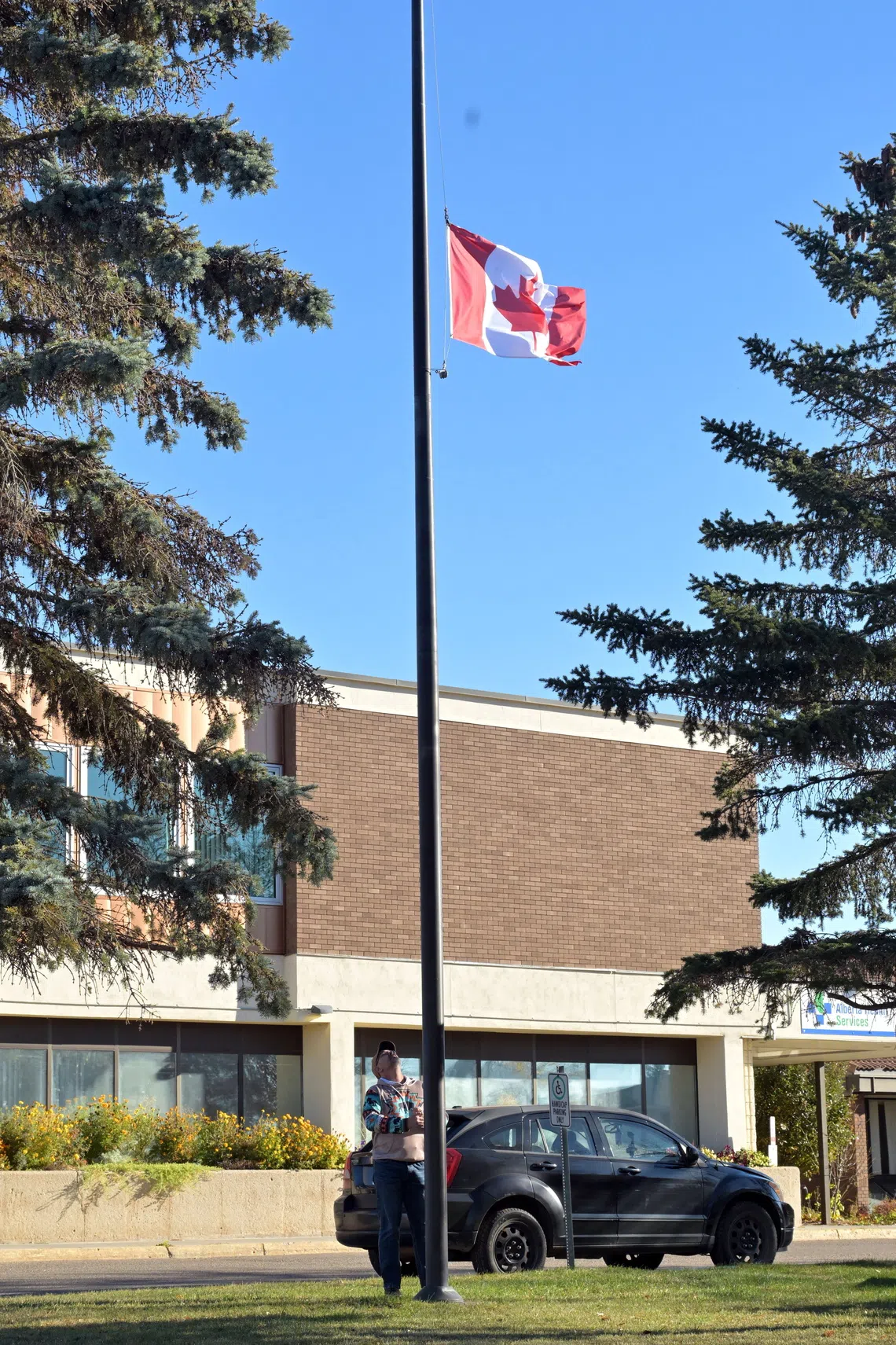A man lowers a flag in front of the Wainwright hospital in Wainwright, Alberta, Canada, on Oct 18.