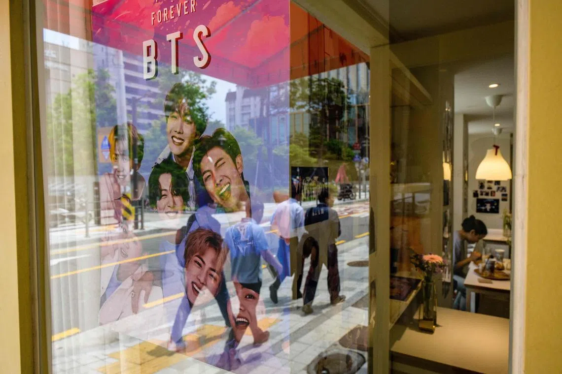 A poster of K-pop megastars BTS outside a cafe in Seoul on Monday. Fans of the K-pop boy band flocked to hot spots around Seoul to mark the supergroup's 10-year anniversary, with South Korea unveiling a special commemorative stamp series to celebrate. 