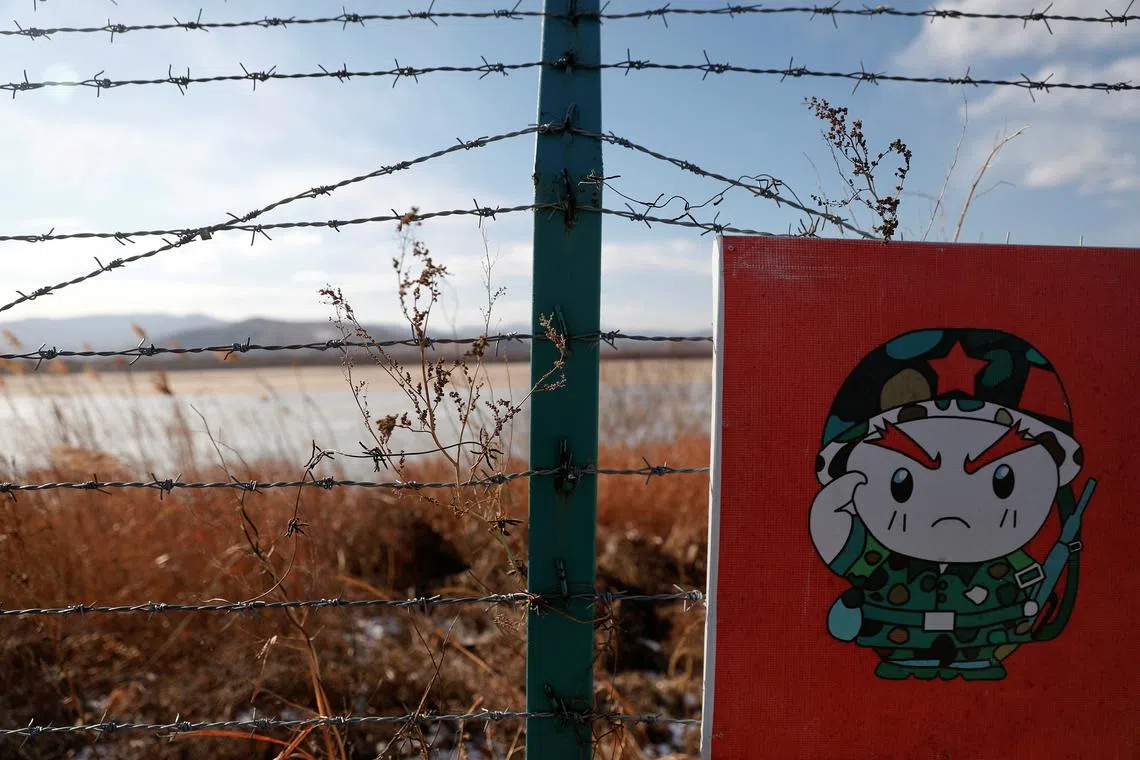 FILE PHOTO: A cartoon soldier is depicted on part of a warning sign on barbed wire on the Chinese side of the border between Russia, China and North Korea near the town of Hunchun, China, November 24, 2017. REUTERS/Damir Sagolj/File Photo