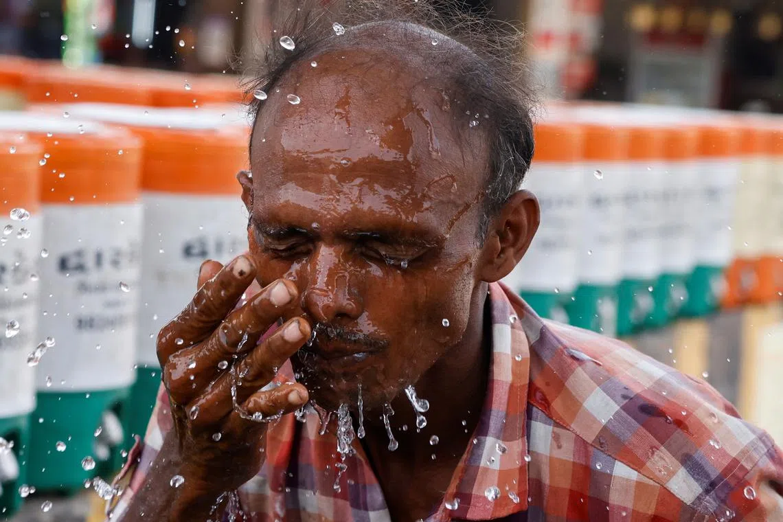 A man sprays cold water on his face from a water jar during a heatwave in Ahmedabad, India, May 29, 2024. REUTERS/Amit Dave
