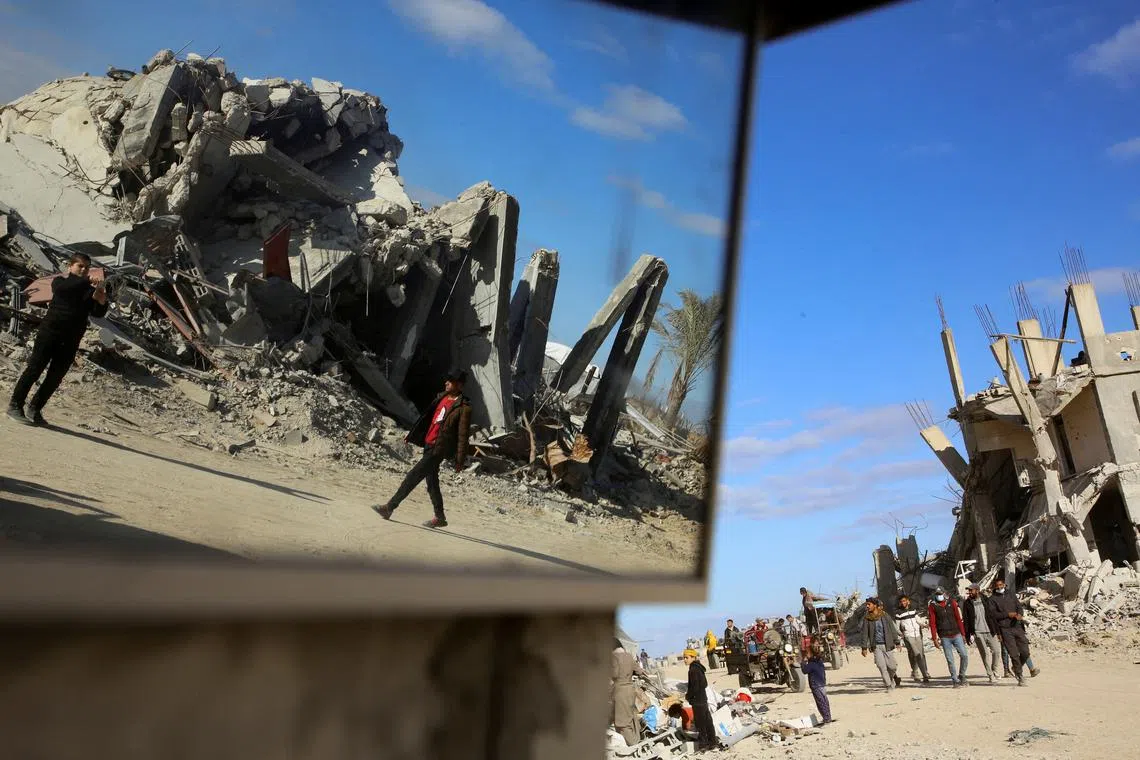 Palestinians walk past the rubble of houses and buildings destroyed during the war, following a ceasefire between Israel and Hamas, in Rafah in the southern Gaza Strip, January 20, 2025. REUTERS/Hatem Khaled