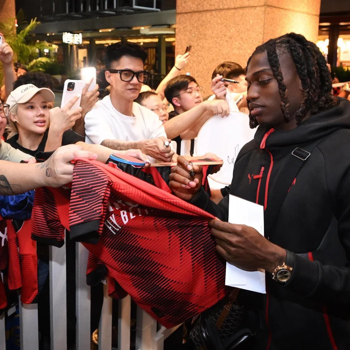 AC Milan's Rafael Leao signing autographs for fans at the Conrad Singapore Marina Bay hotel on July 20, 2025, after arriving just before midnight.