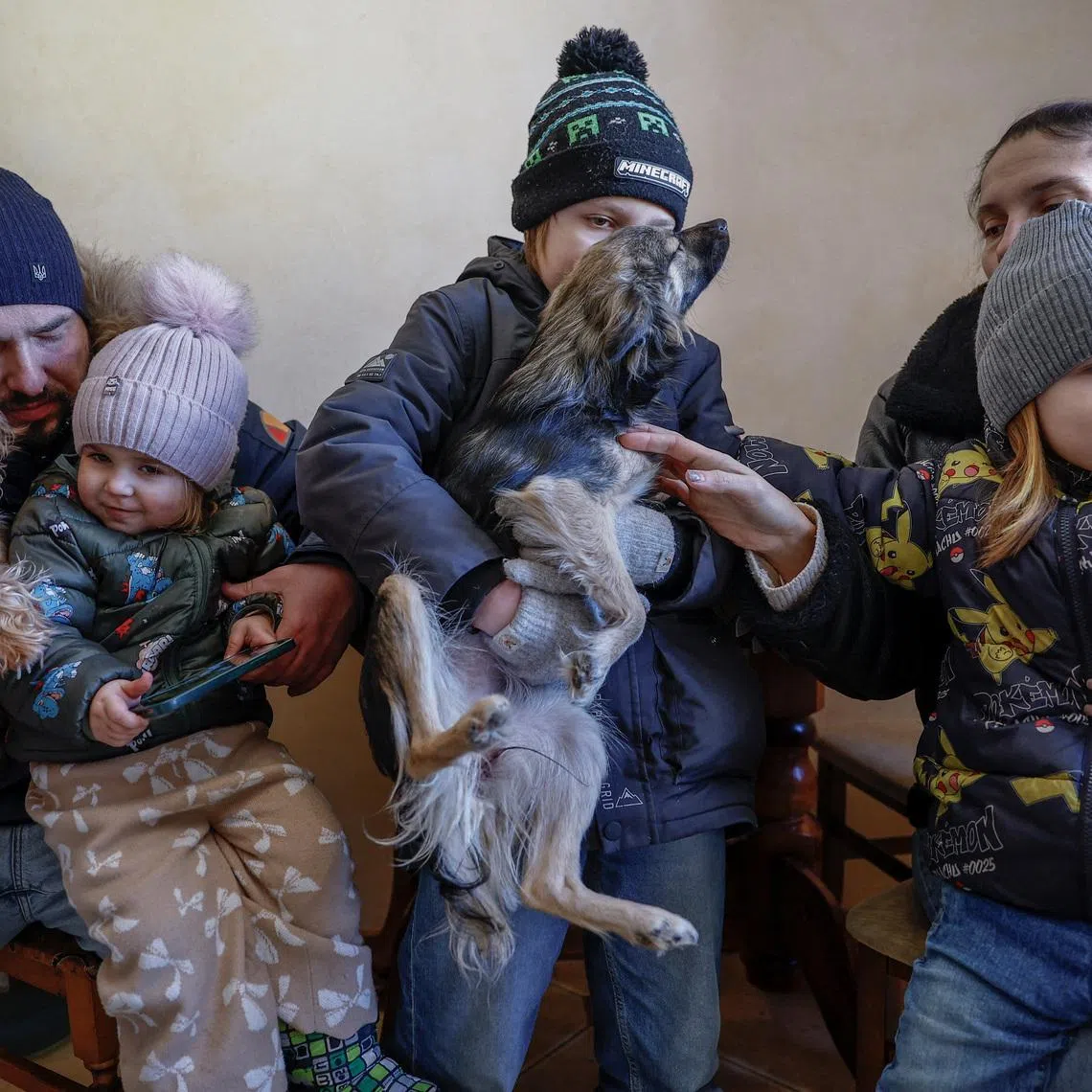 The Davydenko family (from left to right): Denys, 40, Yuliia, 40, and their children Maksym, 11, Tymofiy, 6, and Stephanie, 2 pose for a picture wearing winter clothes in the kitchen of their apartment, which has no heating or hot water and experiences frequent power outages amid Russia's attack on Ukraine, in Kyiv, Ukraine, February 1, 2026. Waves of Russian attacks over the past four months left hundreds of thousands without electricity and water, making this the most devastating winter since the war started; and so the Davydenko family made the choice to stay at the family-owned Piggy Cafe Kyiv - with power supplied by a generator and heating. \"Maksym likes it,\" Denys joked about their new reality. \"He actually says that at home we have to do household chores. Now there's no dish-washing, cleaning, walking the dogs. So he is happy about that.\" REUTERS/Alina Smutko