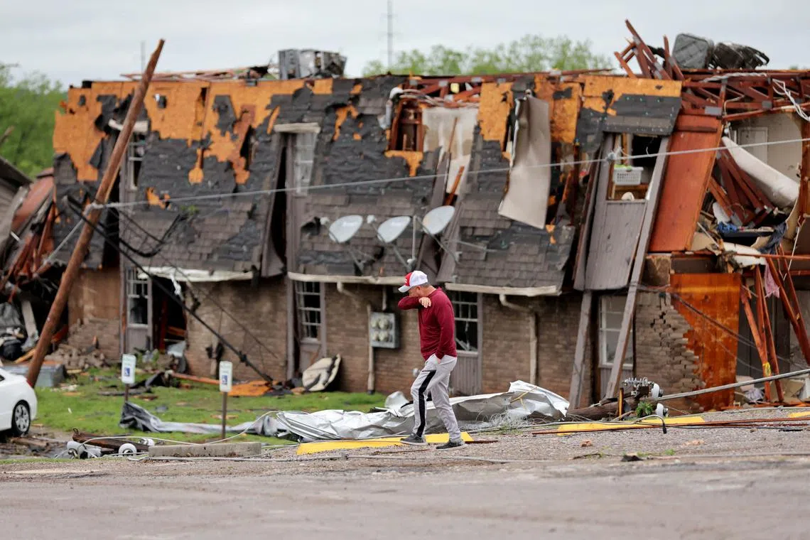 A man walks past a damaged building after it was hit by a tornado the night before in Sulphur, Oklahoma.